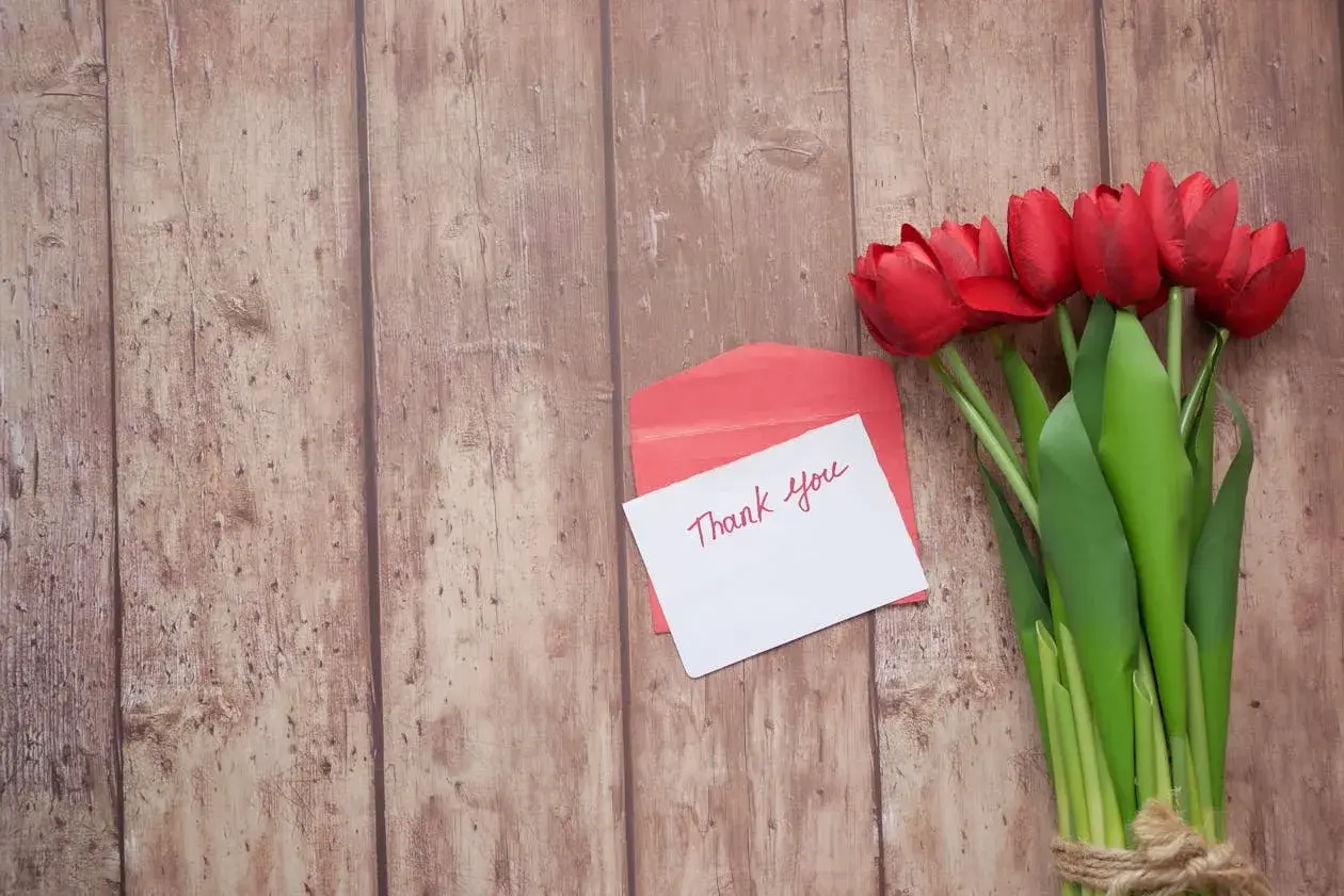 A bouquet of flowers with a handwritten thank you card