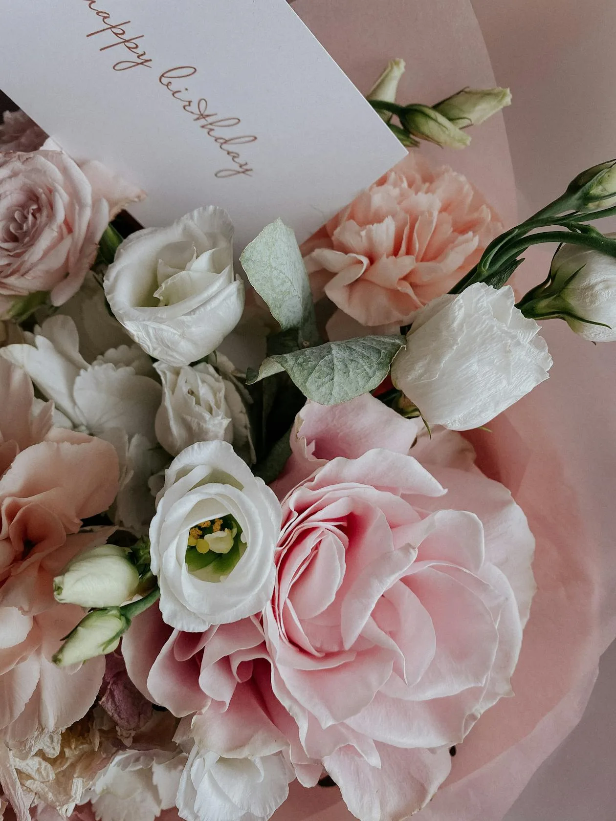 A bouquet of flowers with a happy birthday gift tag attached